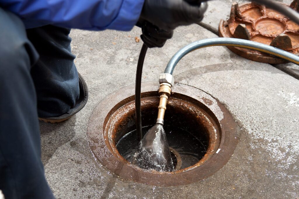 Plumber hydro jetting a sewer line through a manhole in Vancouver