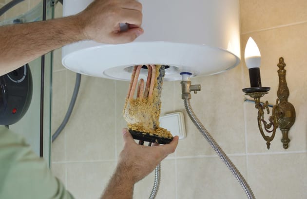Technician removing mineral buildup from a water heater in Vancouver